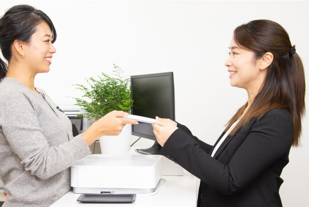 プロカメラマンが撮影データと就活用の証明写真を女子就活生に渡している写真